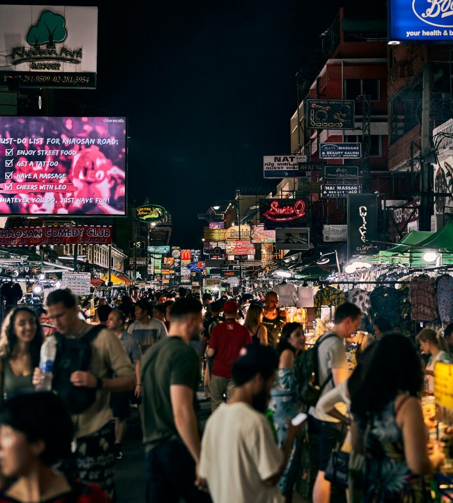 a crowd of people walking down a street next to tall buildings